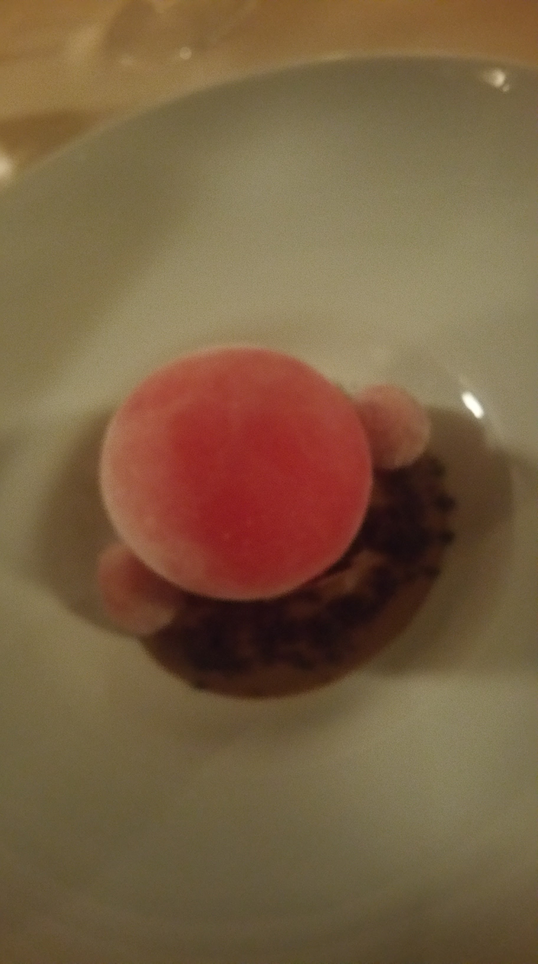 Sfera ghiacciata ai frutti rossi su crema al tè con lamponi cristallizzati